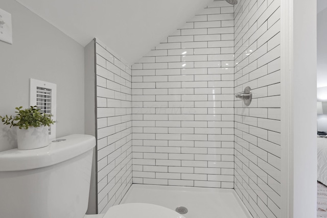 bathroom with tiled shower, vaulted ceiling, and toilet