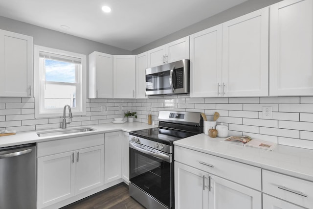 kitchen featuring white cabinets, decorative backsplash, dark wood-type flooring, and appliances with stainless steel finishes