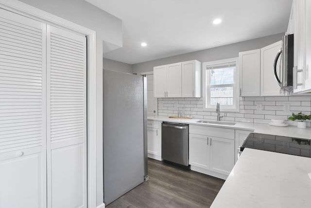 kitchen with dark wood-type flooring, sink, tasteful backsplash, white cabinetry, and stainless steel appliances