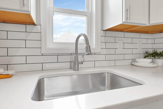 details featuring white cabinets, sink, and tasteful backsplash