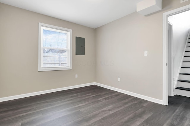 empty room featuring electric panel and dark wood-type flooring