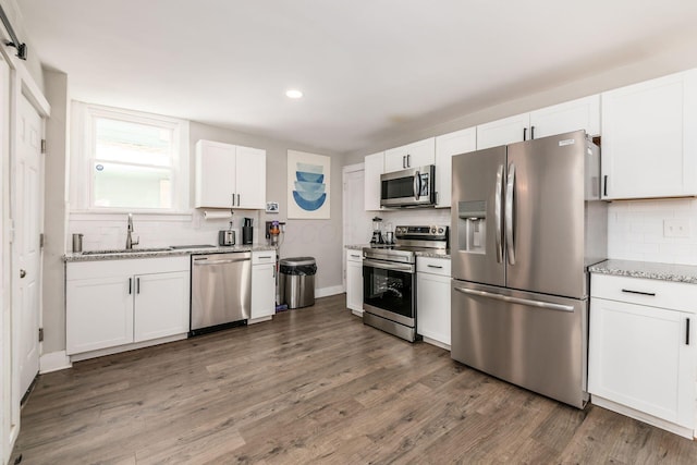 kitchen featuring light stone countertops, white cabinetry, sink, dark wood-type flooring, and stainless steel appliances