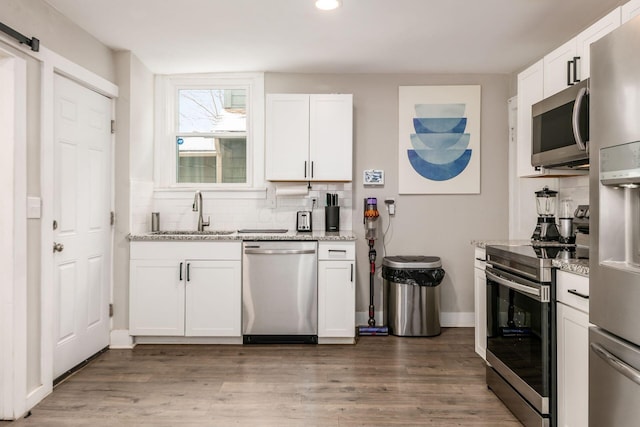 kitchen featuring a barn door, white cabinetry, sink, and appliances with stainless steel finishes