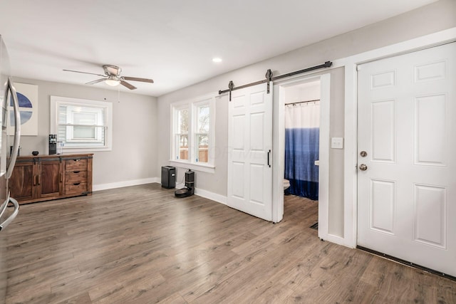 bedroom with hardwood / wood-style floors, a barn door, and ceiling fan