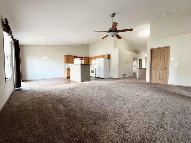 unfurnished living room with track lighting, high vaulted ceiling, ceiling fan with notable chandelier, and dark colored carpet