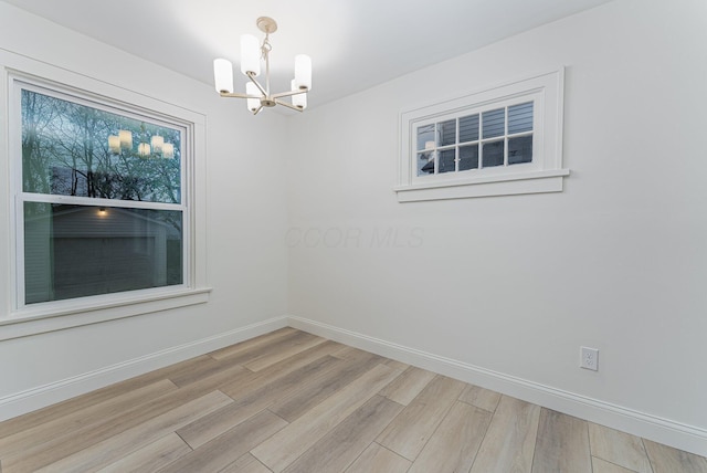 unfurnished room featuring a notable chandelier and light hardwood / wood-style flooring