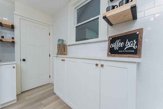 interior space featuring tasteful backsplash, white cabinetry, and light hardwood / wood-style flooring