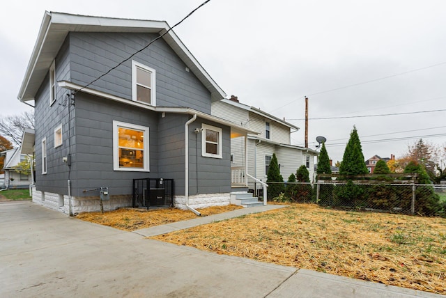 rear view of property featuring central air condition unit and a yard