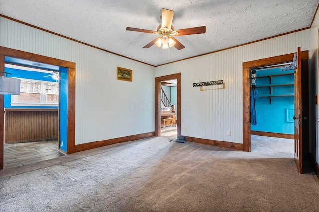 unfurnished room featuring ceiling fan, crown molding, carpet, and a textured ceiling