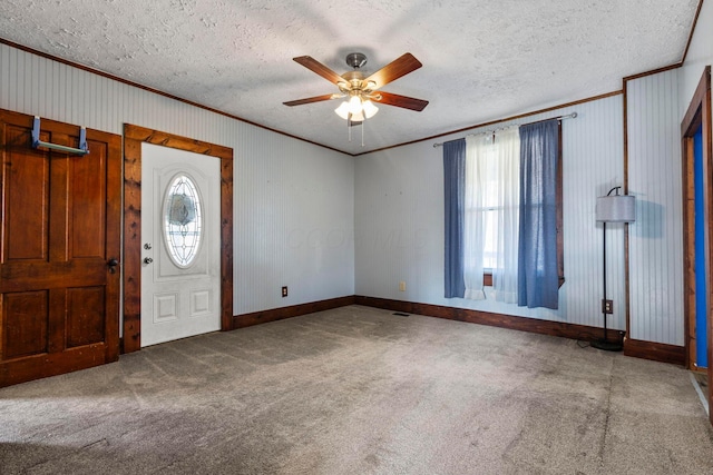 foyer with ceiling fan, carpet floors, a textured ceiling, and ornamental molding