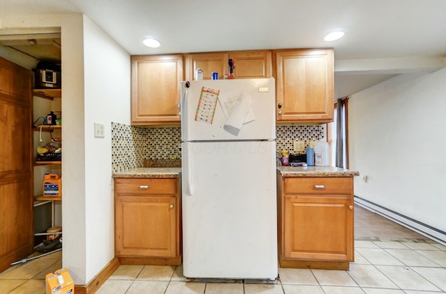 kitchen featuring white refrigerator, light tile patterned floors, backsplash, and a baseboard heating unit