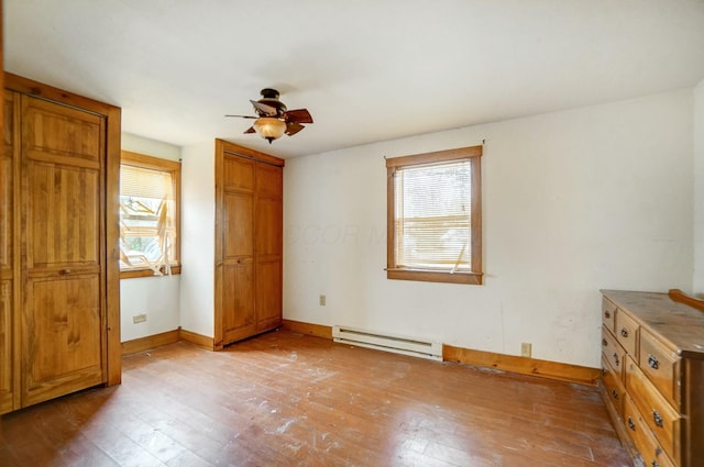 unfurnished bedroom featuring ceiling fan, baseboard heating, and light hardwood / wood-style flooring