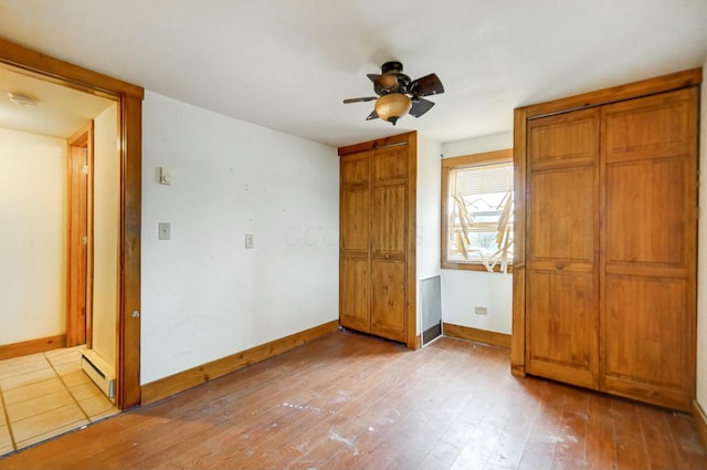 unfurnished bedroom featuring ceiling fan, a baseboard radiator, and light wood-type flooring