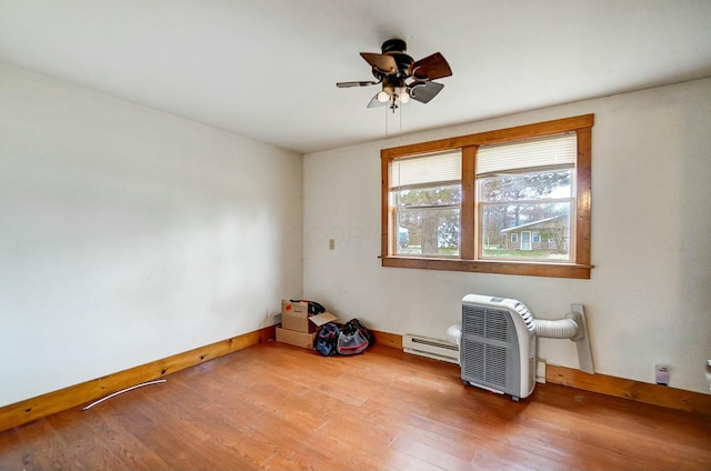 empty room with ceiling fan, hardwood / wood-style floors, and a baseboard heating unit