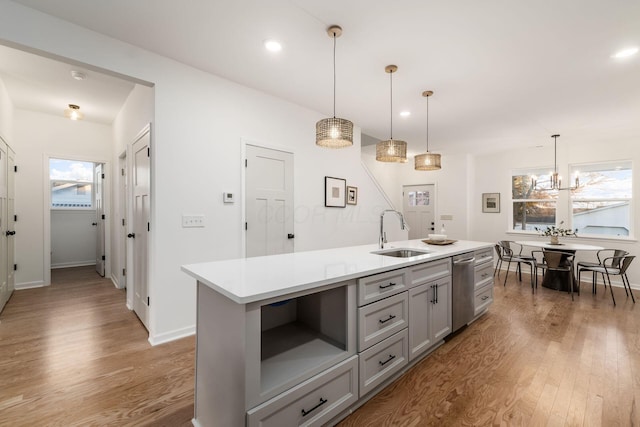 kitchen with sink, decorative light fixtures, a center island with sink, gray cabinets, and hardwood / wood-style flooring