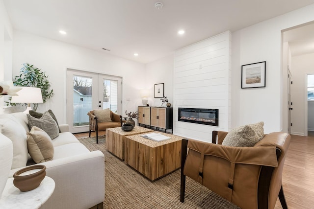 living room featuring french doors, a fireplace, and light wood-type flooring