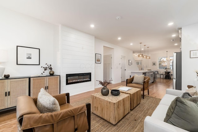 living room with a fireplace, sink, and light wood-type flooring