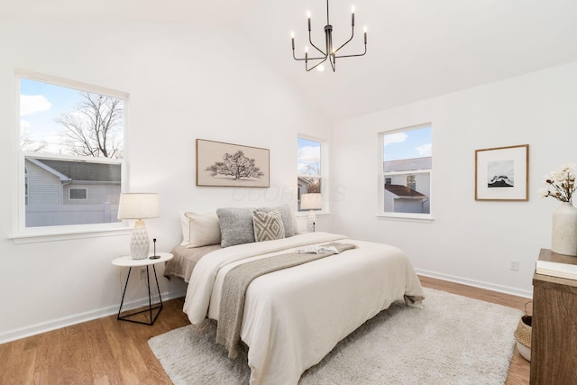 bedroom featuring an inviting chandelier, high vaulted ceiling, and light wood-type flooring