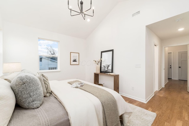 bedroom featuring high vaulted ceiling, a chandelier, and light wood-type flooring