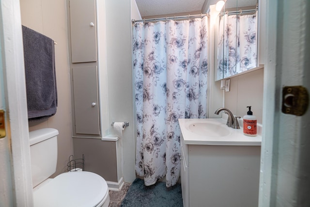 full bathroom featuring curtained shower, toilet, vanity, and a textured ceiling