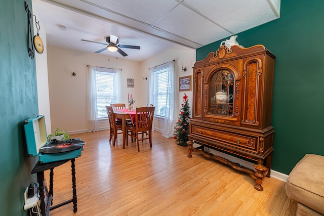 dining area featuring baseboards, ceiling fan, and light wood finished floors