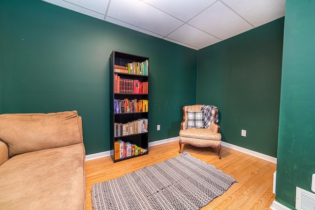 sitting room featuring a drop ceiling, visible vents, baseboards, and wood finished floors