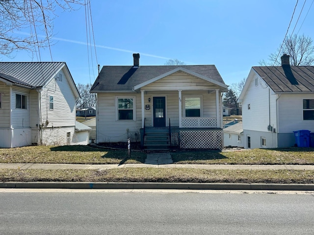 bungalow-style house featuring covered porch and a front yard