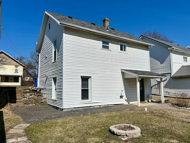 back of house with a fire pit and a chimney