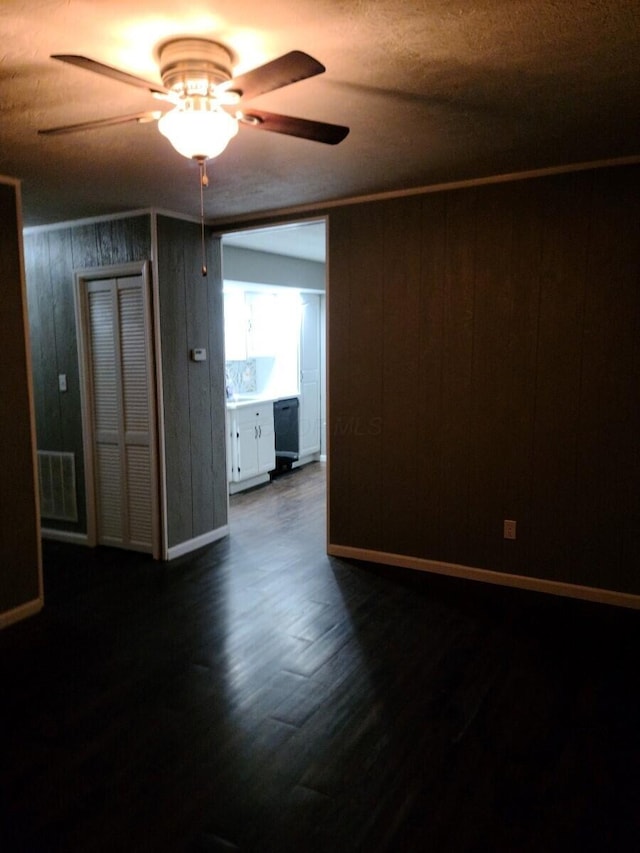 unfurnished room featuring dark hardwood / wood-style flooring, ceiling fan, and wood walls