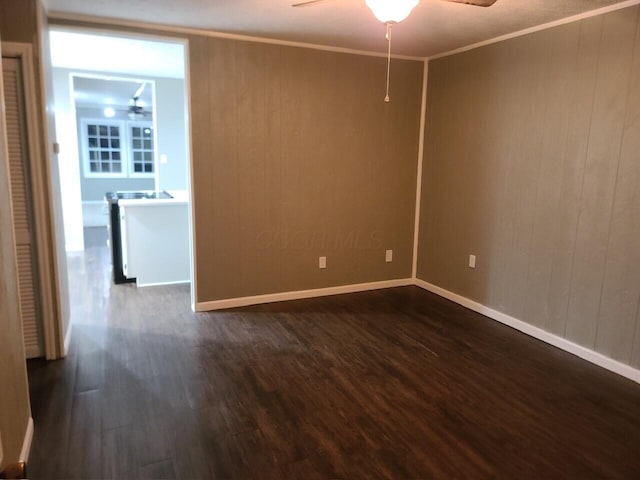 unfurnished room featuring wooden walls, dark hardwood / wood-style floors, ceiling fan, and ornamental molding