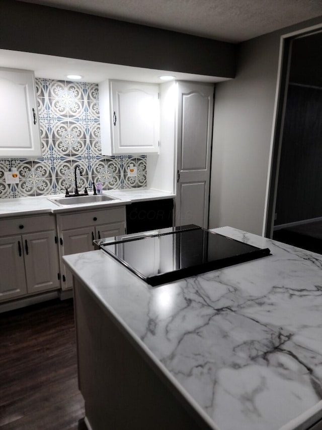 kitchen with backsplash, white cabinets, sink, dark hardwood / wood-style floors, and black electric cooktop