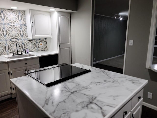 kitchen with black electric stovetop, backsplash, sink, white cabinets, and dark hardwood / wood-style floors