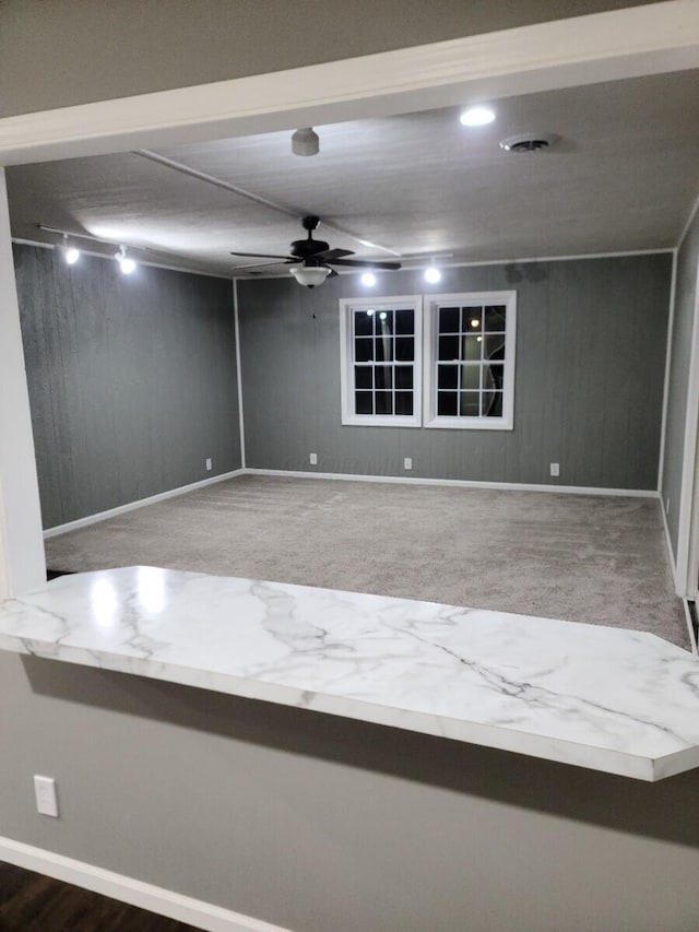 unfurnished room with carpet flooring, ceiling fan, and wood walls