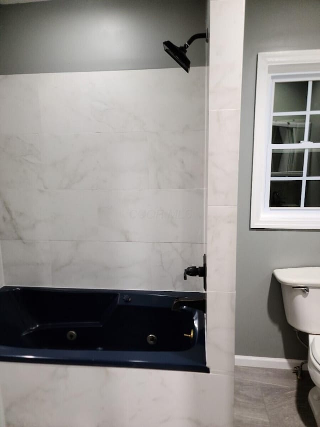 bathroom featuring tiled shower / bath combo and toilet