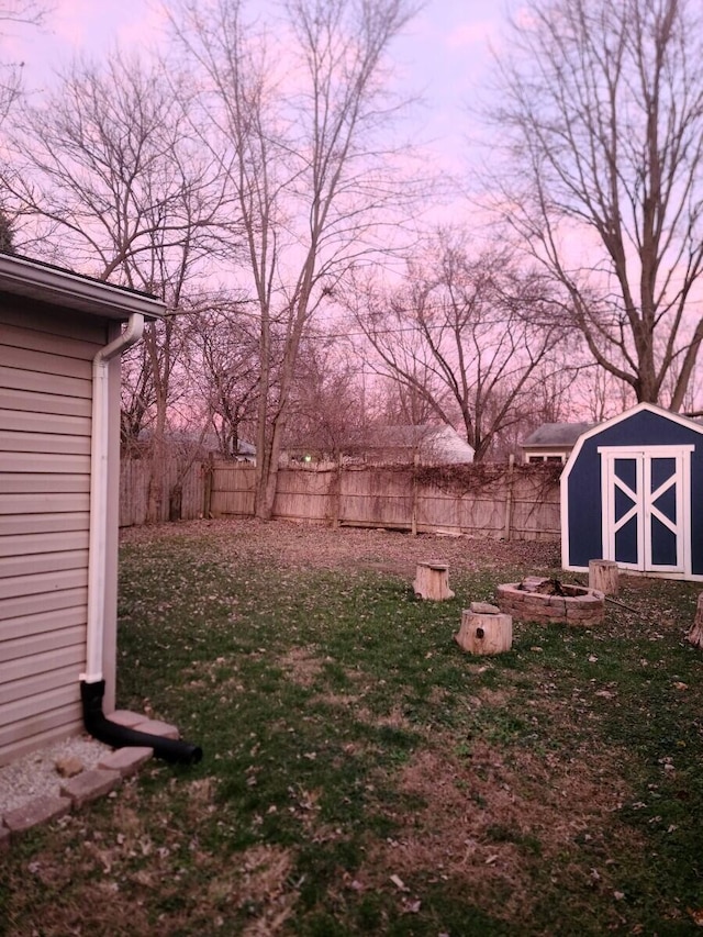 yard at dusk featuring a storage shed