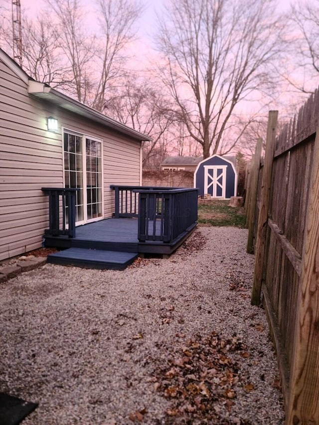 yard at dusk with a storage unit and a wooden deck