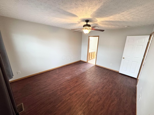 unfurnished bedroom featuring dark wood-style floors, visible vents, baseboards, and a ceiling fan