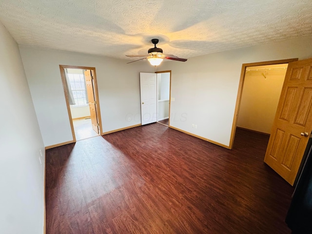 unfurnished room with a textured ceiling, ceiling fan, dark wood finished floors, and baseboards