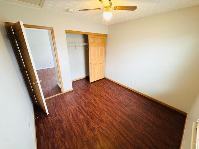 unfurnished bedroom featuring baseboards, ceiling fan, dark wood-type flooring, a textured ceiling, and a closet