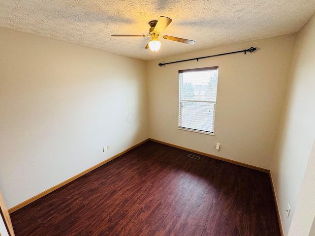 empty room featuring ceiling fan, baseboards, visible vents, and dark wood finished floors