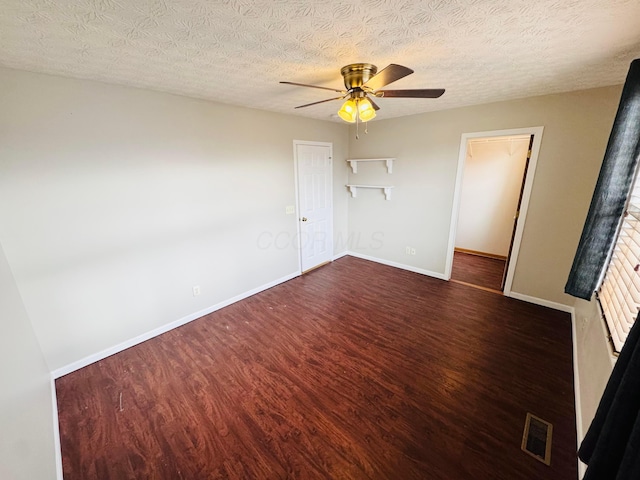 spare room with a textured ceiling, wood finished floors, visible vents, baseboards, and a ceiling fan