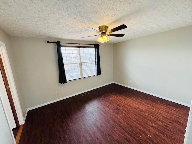 spare room with ceiling fan, dark wood-type flooring, visible vents, and baseboards