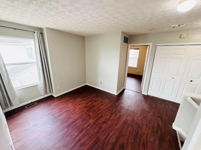 unfurnished bedroom with baseboards, multiple windows, visible vents, and wood finished floors