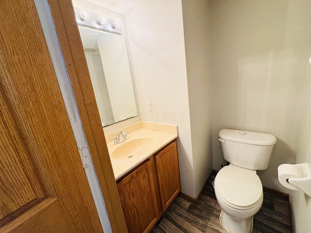 half bath featuring toilet, wood finished floors, and vanity