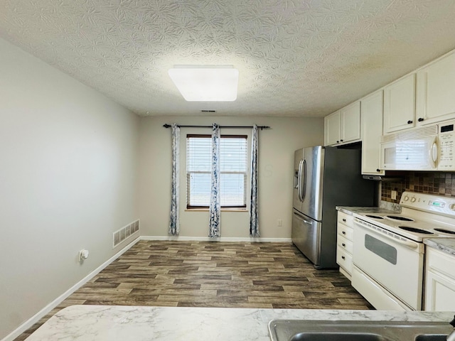 kitchen with white appliances, visible vents, white cabinets, and dark wood-type flooring