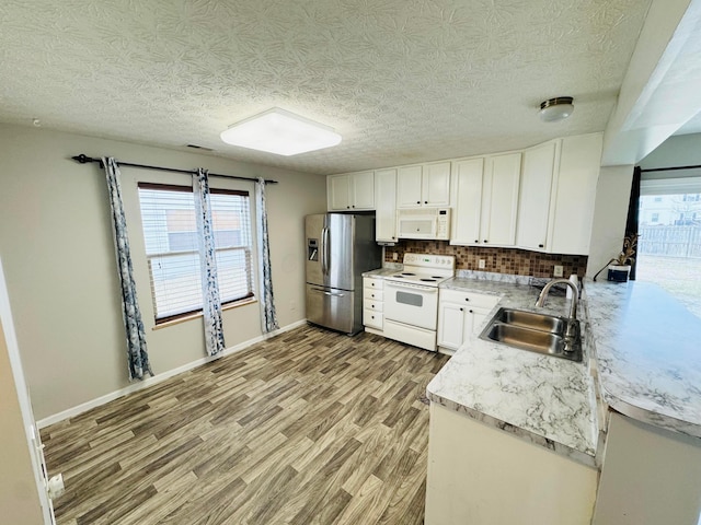 kitchen featuring decorative backsplash, white cabinets, a sink, light wood-type flooring, and white appliances