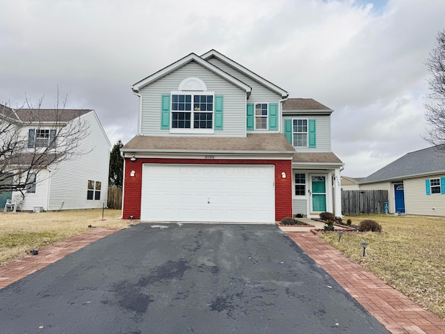 traditional-style home with aphalt driveway, an attached garage, brick siding, fence, and a front lawn