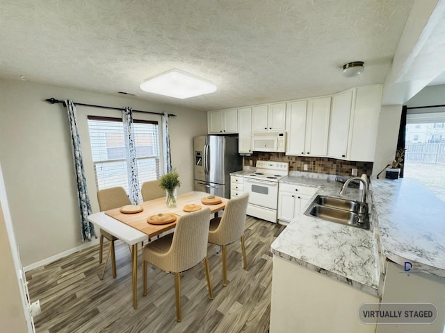 kitchen with light wood-style flooring, white appliances, a sink, white cabinets, and backsplash