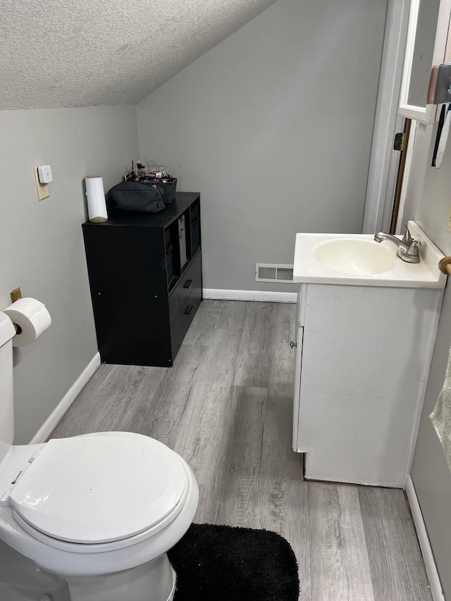 bathroom with toilet, vanity, a textured ceiling, and hardwood / wood-style flooring