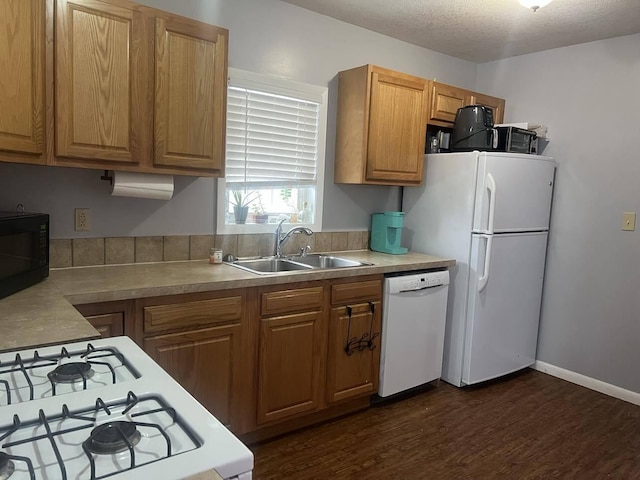 kitchen with sink, dark hardwood / wood-style flooring, white appliances, and a textured ceiling